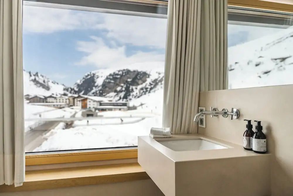 Fenster im Badezimmer mit Blick auf verschneite Berge und Tal.