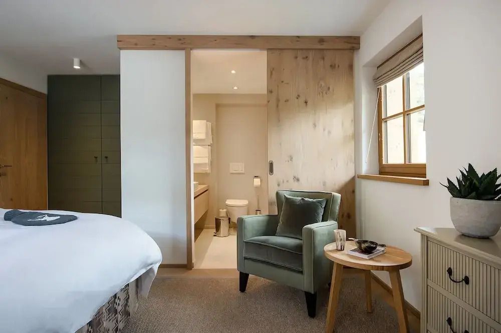 Gemütliches Hotelzimmer mit Sessel und Holzelementen