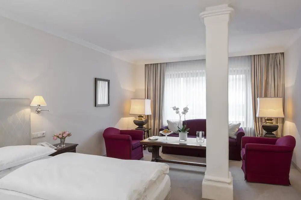 Hotelzimmer mit gemütlicher Sitzecke und weißen Vorhängen