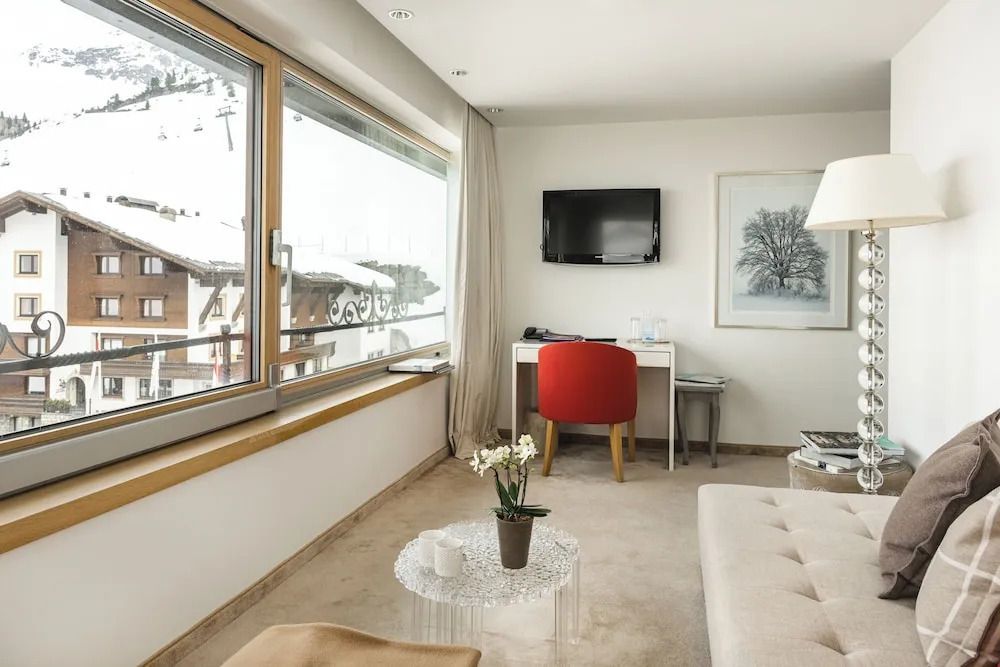 Elegantes Zimmer mit Schreibtisch, Flachbild-TV und großem Fenster mit Schneeblick.