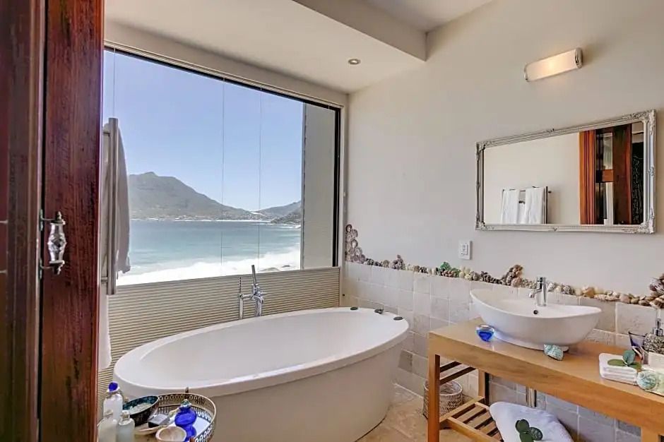 Helles Badezimmer mit freistehender Badewanne und Panoramafenster zum Meer.