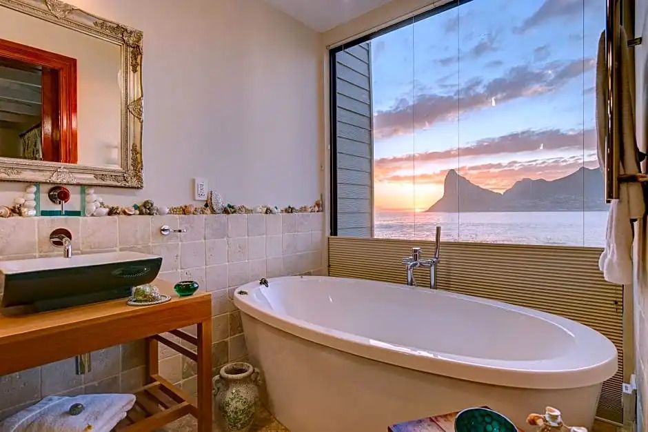 Badezimmer mit freistehender Badewanne und Meerblick bei Sonnenuntergang.