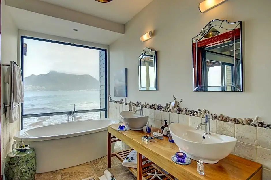Modernes Badezimmer mit Doppelwaschbecken und großer Badewanne mit Meerblick.