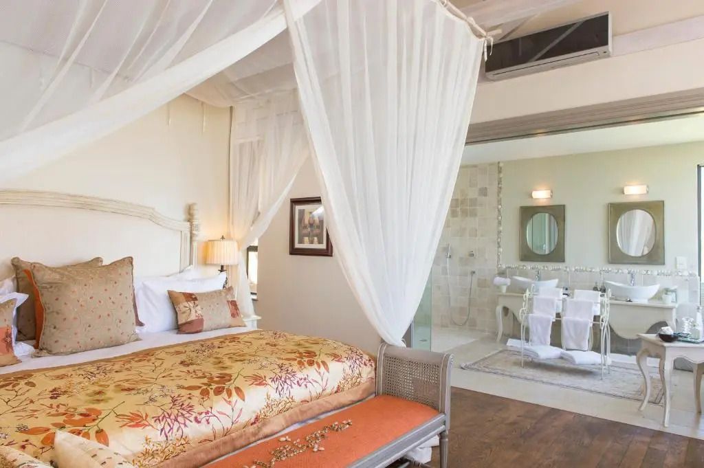 Suite mit Doppelbett und Blick auf offenes Badezimmer mit Dusche