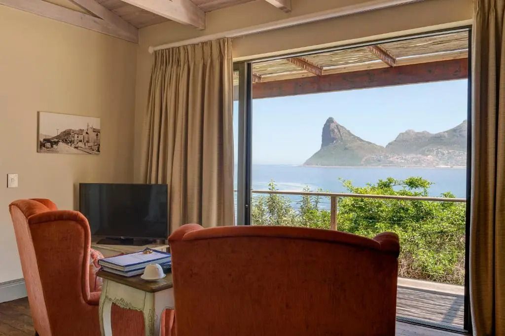 Blick auf das Meer von einer Suite mit zwei Sesseln und Fernseher