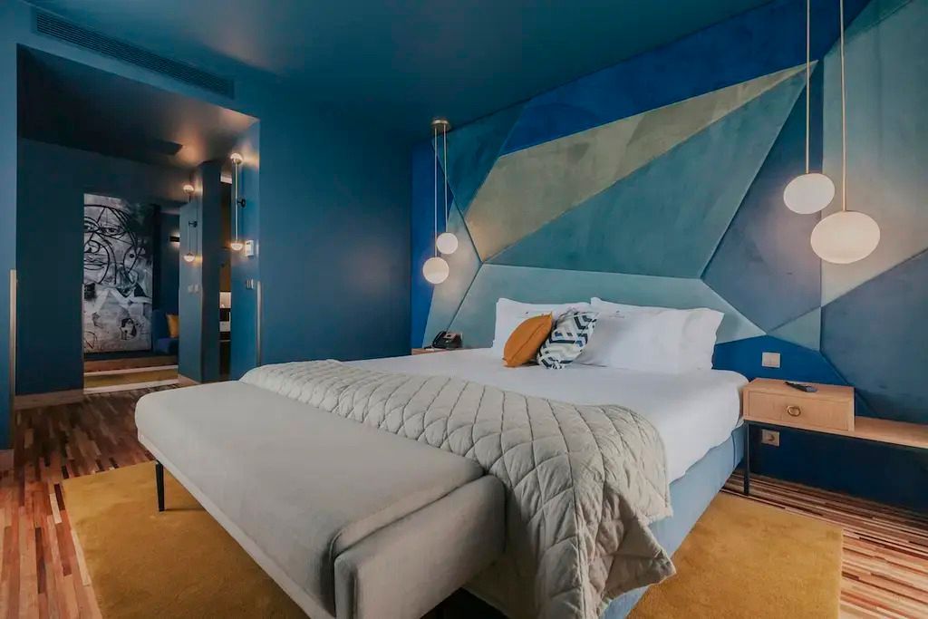 Moderne Deluxe Junior-Suite mit blauem Design und gemütlichem Doppelbett.