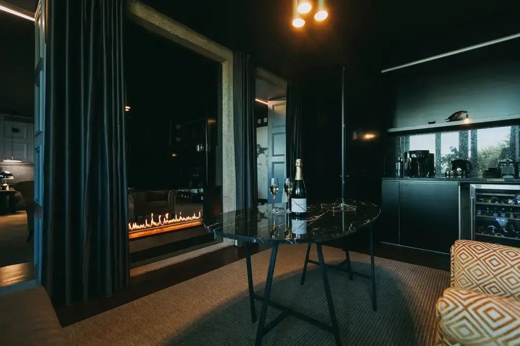 Zimmeransicht mit Kamin und Champagnerflasche auf einem Tisch im Hotel Torel Avantgarde