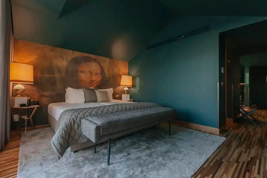 Stilvoll eingerichtetes Hotelzimmer mit Kunstwerk und modernem Doppelbett.