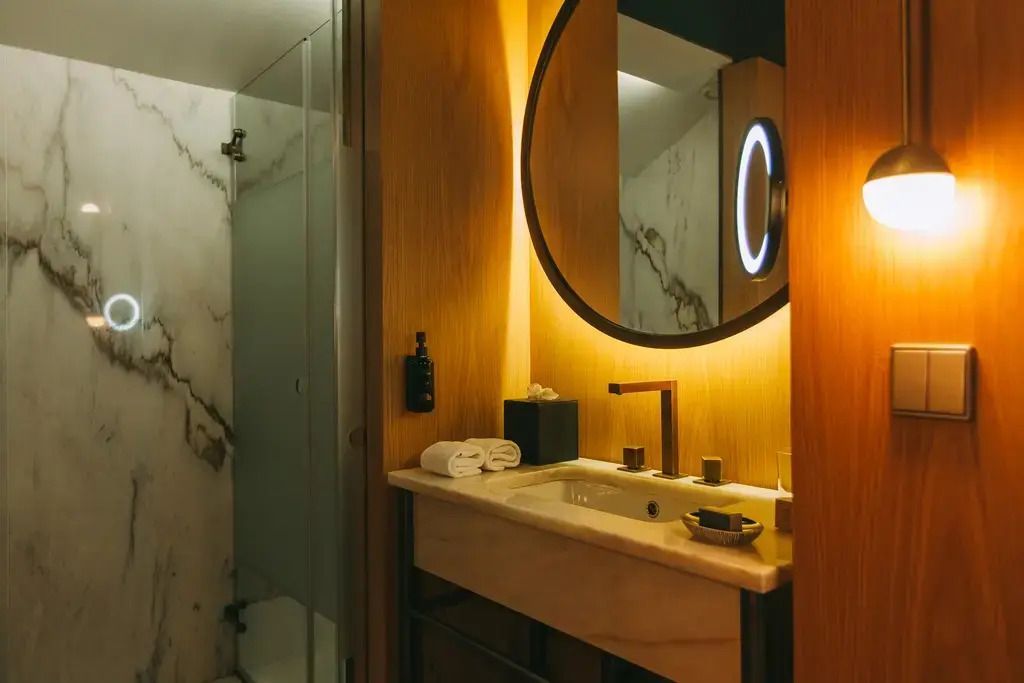 Luxuriöses Badezimmer mit Marmorakzenten und beleuchtetem Spiegel.