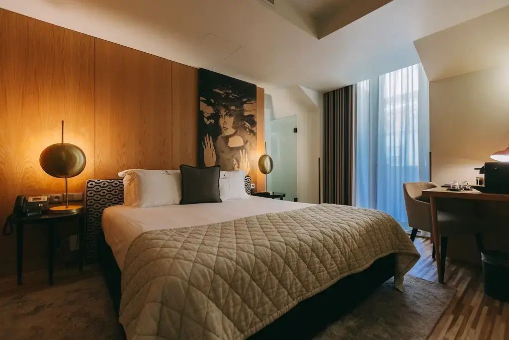 Geräumiges Hotelzimmer mit Kunstwerk an der Wand und einladendem Doppelbett.