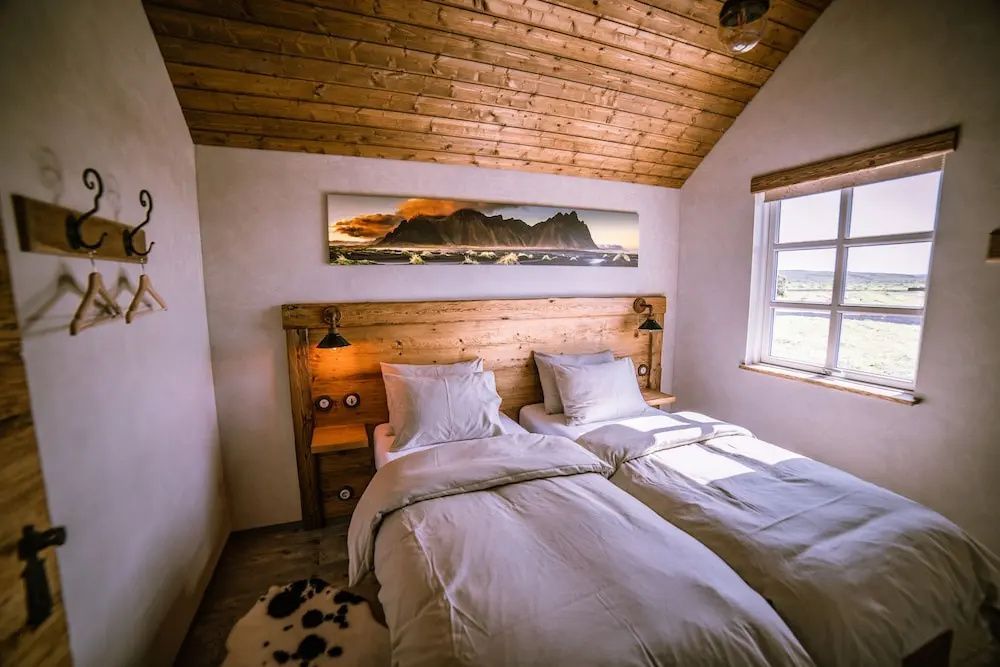 Gemütliches Schlafzimmer mit Holzdecke und zwei Einzelbetten im Torfhús Retreat.