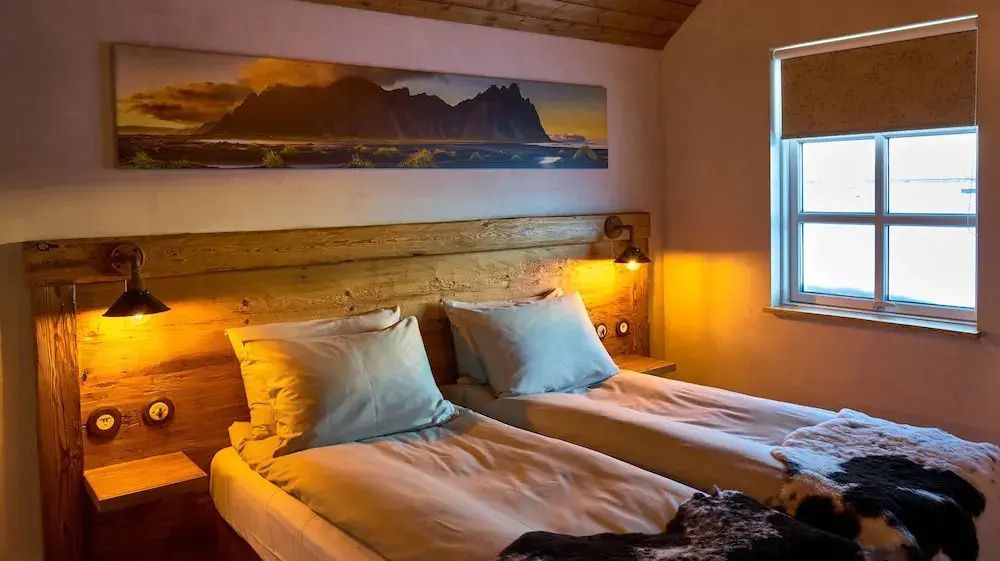 Schlafzimmer im Torfhús Retreat mit stimmungsvoller Beleuchtung und Holzdetails.
