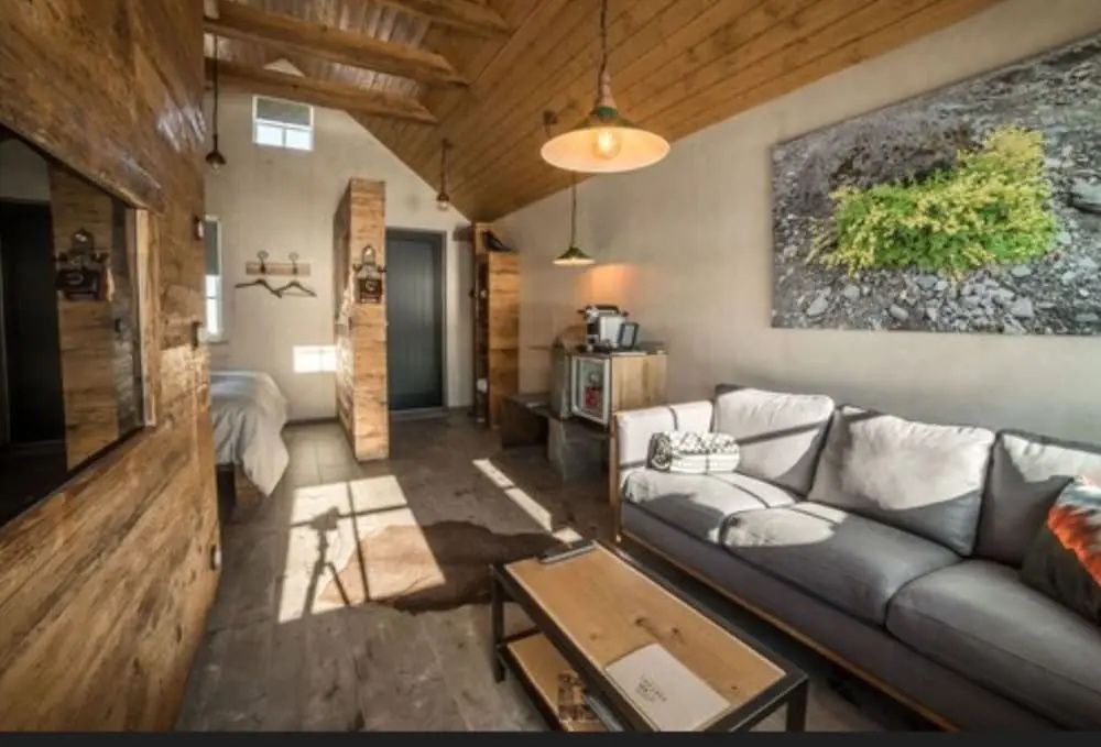 Lichtdurchfluteter Wohnbereich einer Suite mit gemütlichem Sofa und rustikaler Holzeinrichtung.