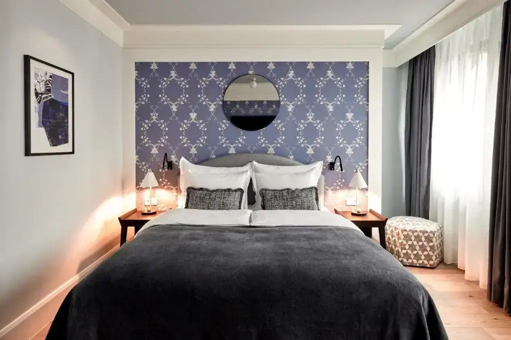 Elegantes Hotelzimmer mit Doppelbett, blauer Akzenttapete und Beleuchtung.