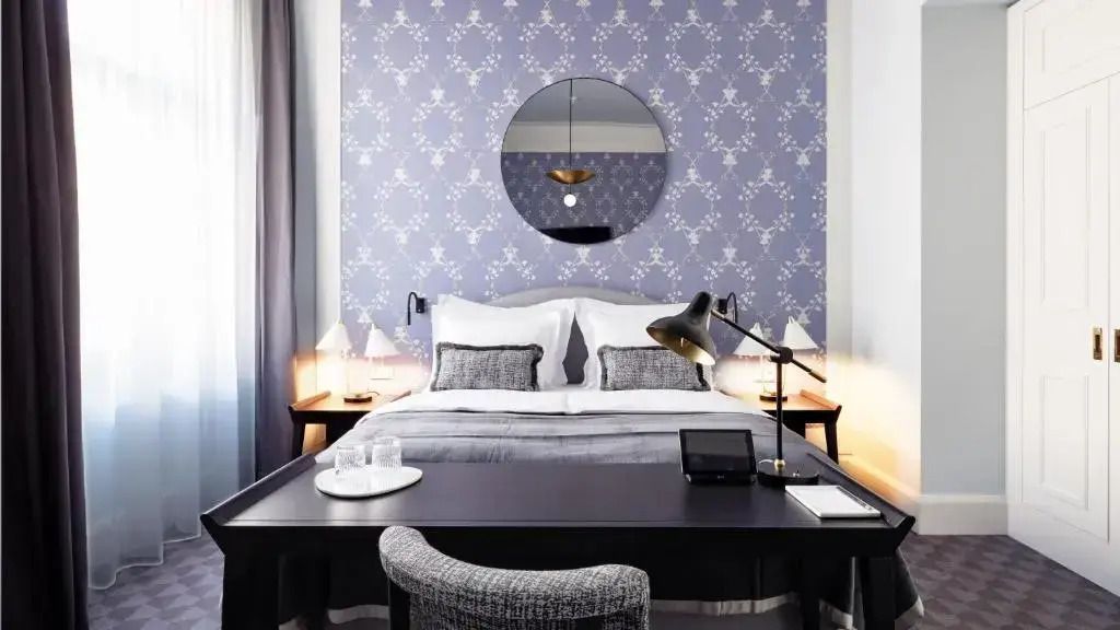 Geschmackvoll gestaltetes Zimmer mit Schreibtisch und Doppelbett, blaue Tapete.