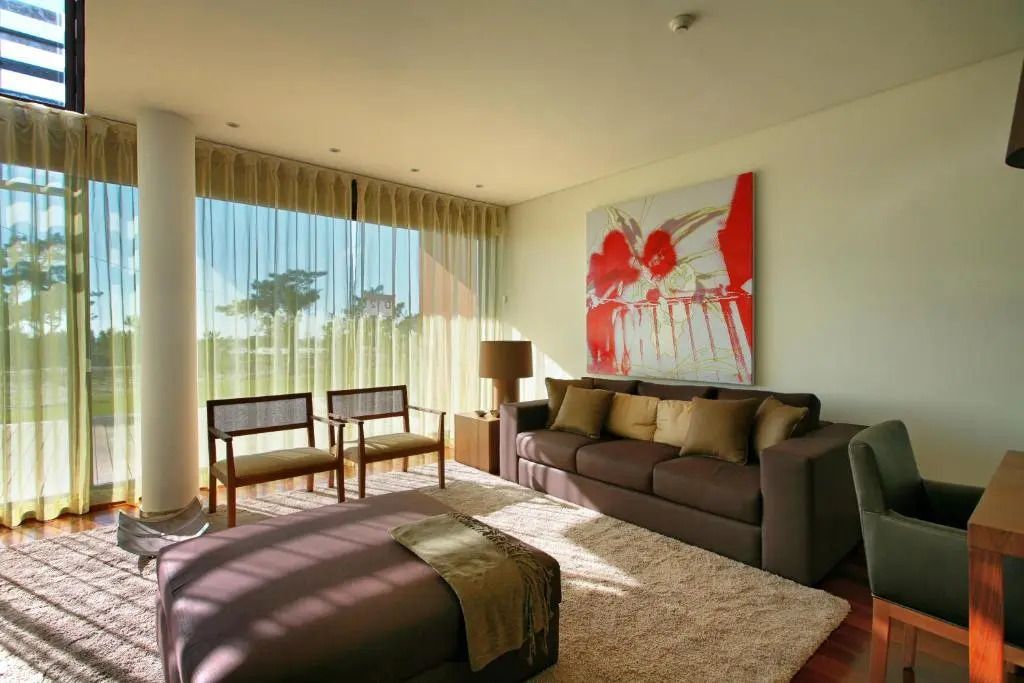 Sonniges Wohnzimmer mit Sofas und großen Fenstern sowie Kunstbild an Wand
