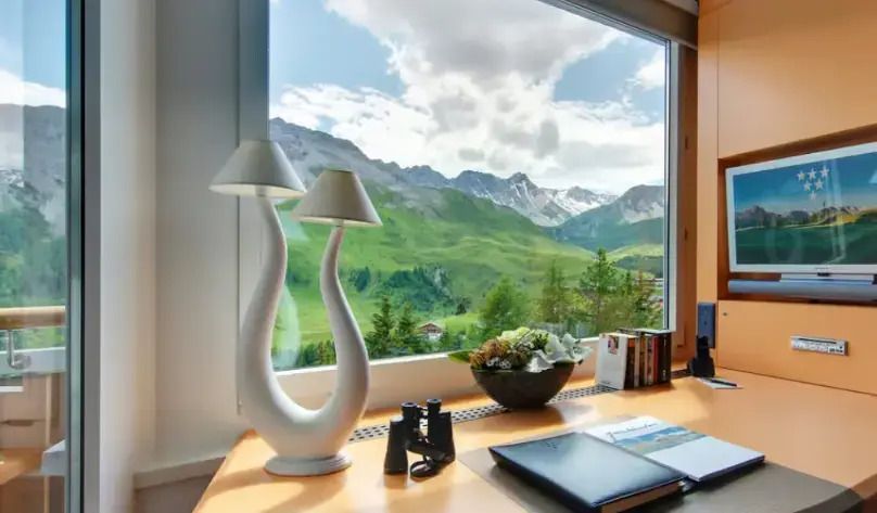 Schreibtisch mit Ausblick auf grüne Berge und moderne Lampen