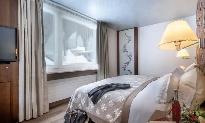 Helles Schlafzimmer mit gemütlichem Dekor und Blick auf schneebedeckte Landschaft