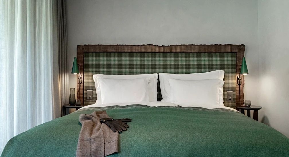 Komfortables Bett mit grünem Überwurf und eleganter Beleuchtung