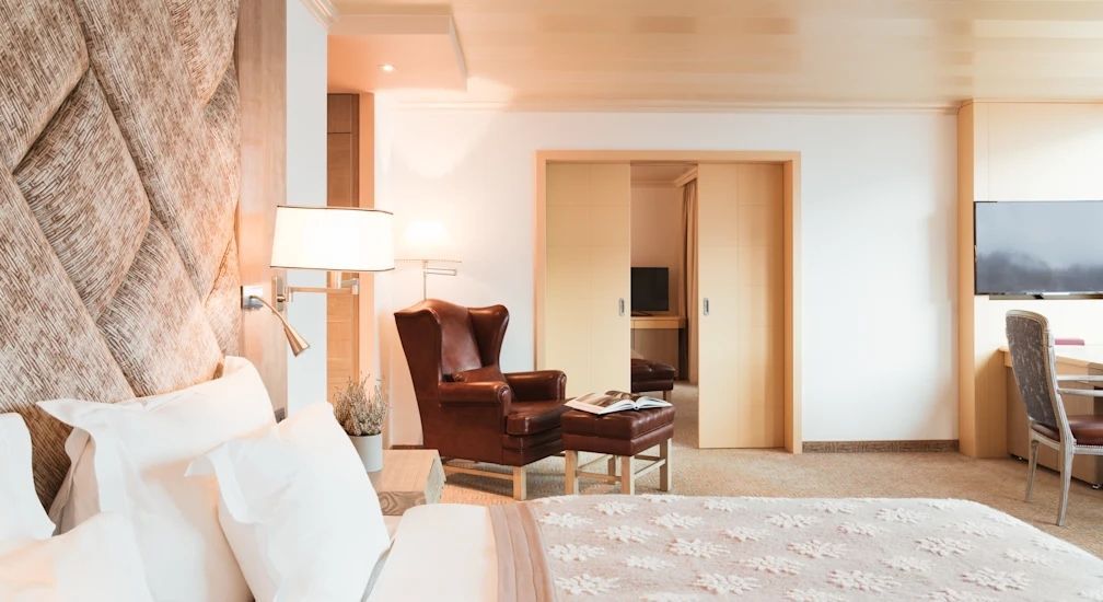 Gemütlicher Sitzbereich in einer Suite mit Ledersessel und flauschigem Teppich