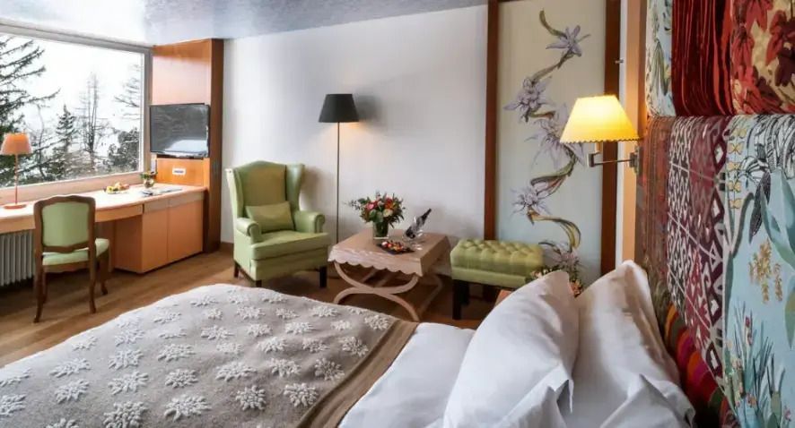 Gemütliche Sitzecke im Hotelzimmer mit grünen Sesseln und frischen Blumen