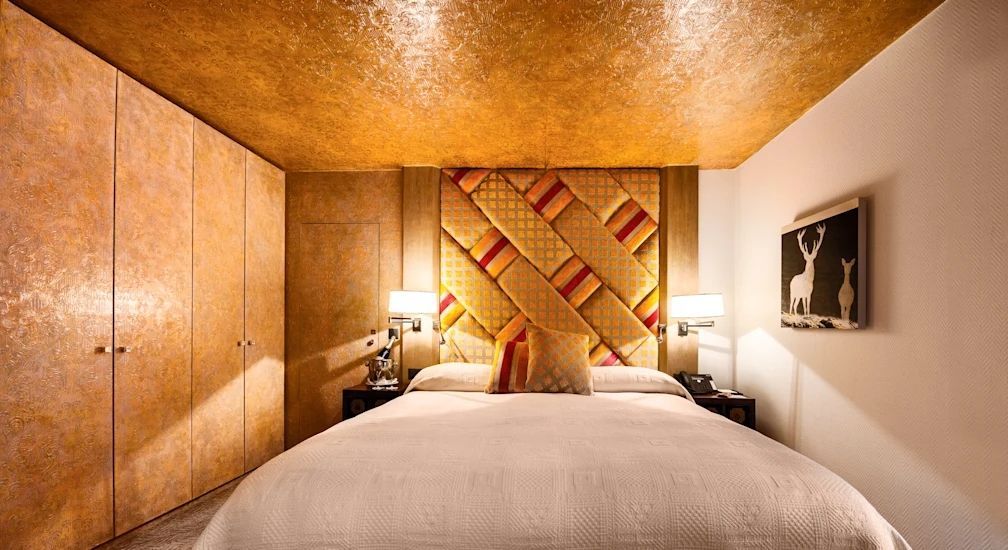 Luxuriöses Schlafzimmer mit goldener Decke und gestepptem Kopfteil.