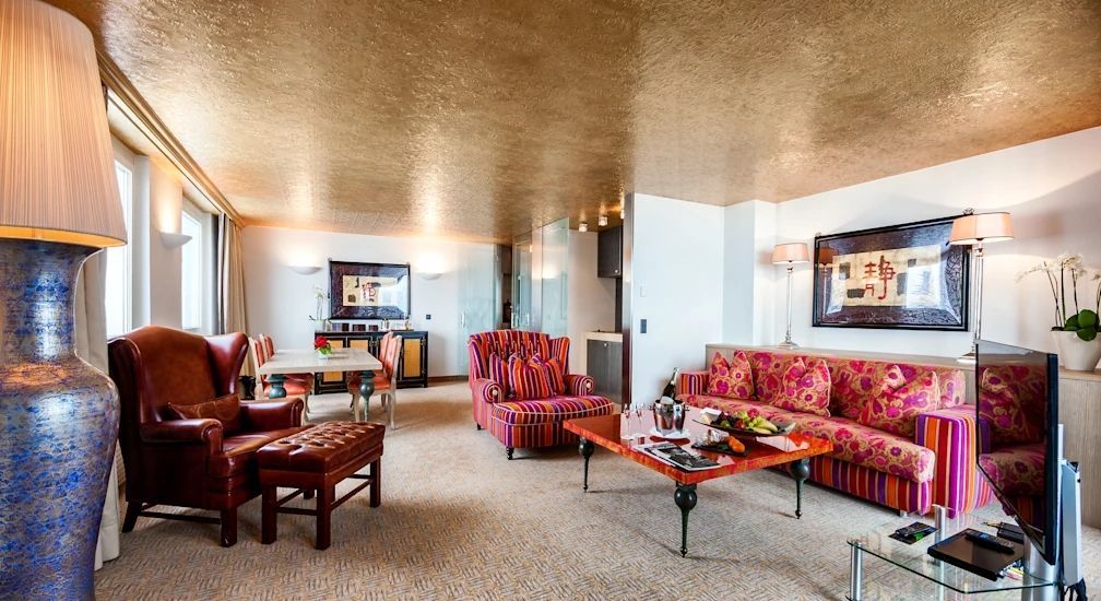 Luxuriöser Suite-Wohnbereich mit zwei Sofas und goldenem Deckenfinish.