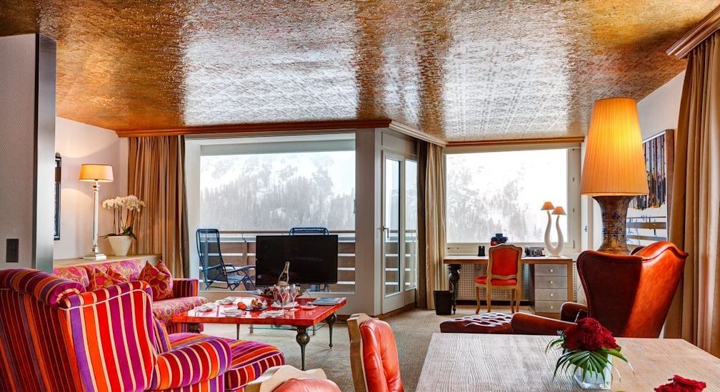 Wohnzimmer mit Balkonzugang und bergiger Schneelandschaft im Hintergrund.