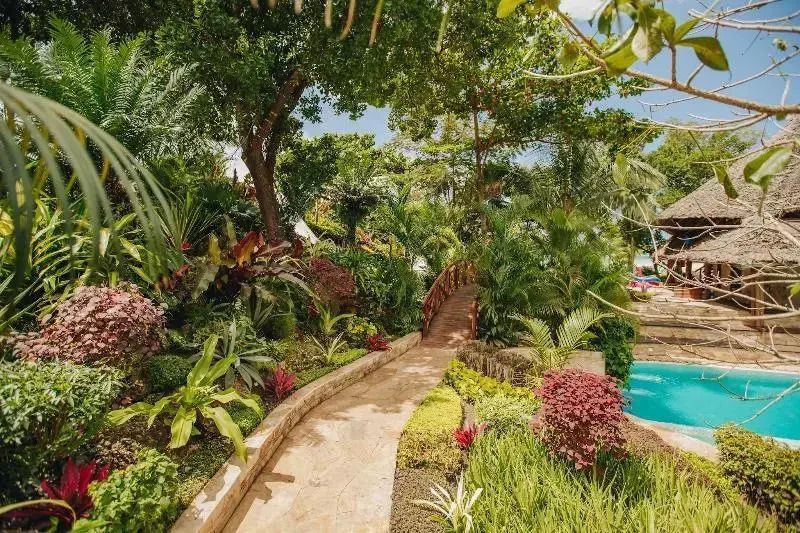 Üppiger tropischer Garten mit Pfad und Pool im Tulia Zanzibar Resort