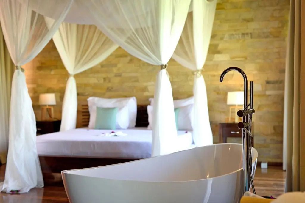 Freistehende Badewanne in einem luxuriösen Schlafzimmer mit Himmelbett