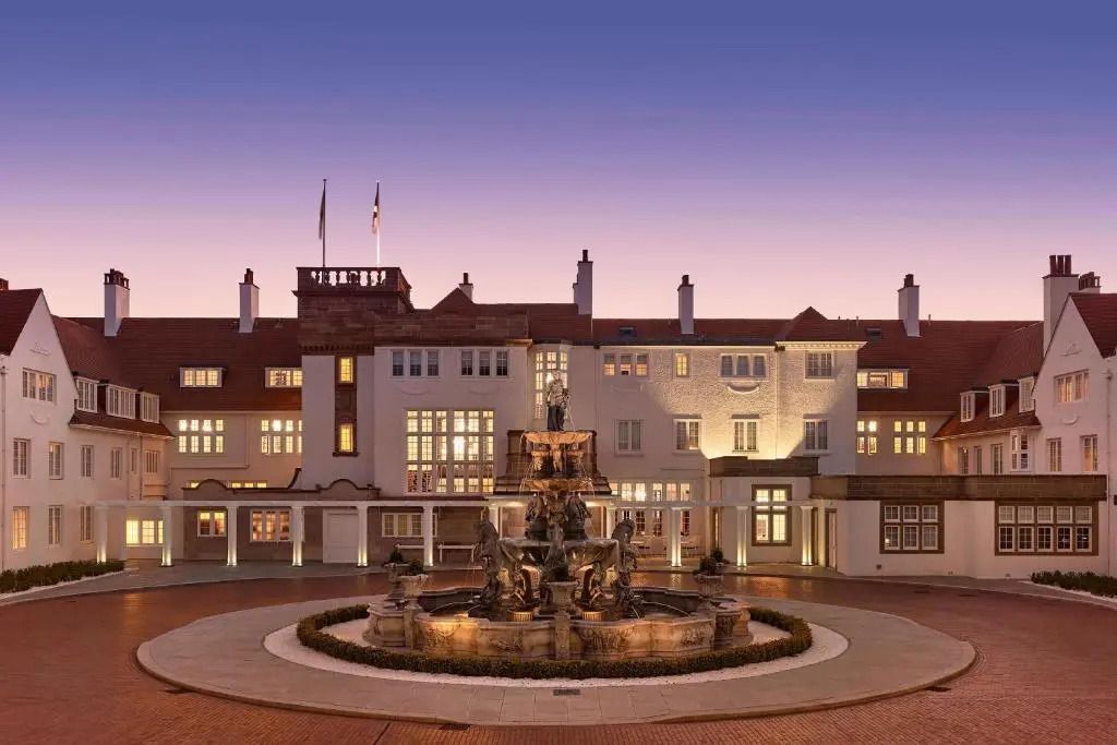Elegante Fassade des Trump Turnberry Hotels bei Sonnenuntergang mit beleuchtetem Springbrunnen