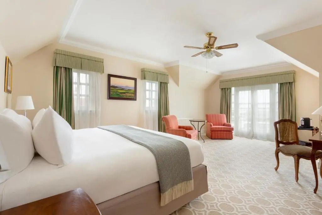 Geräumiges Schlafzimmer mit bequemen Sesseln und einem Deckenventilator im Trump Turnberry Scotland.