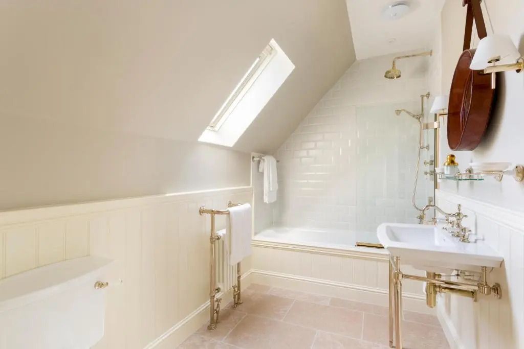 Helles Badezimmer unter Schrägdach mit Badewanne und eleganten Armaturen