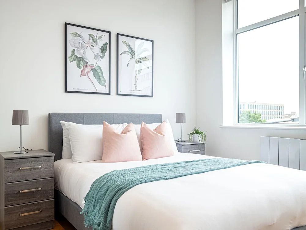 Schlafzimmer in neutralem Design mit großen Fenstern und Pflanzenkunst.