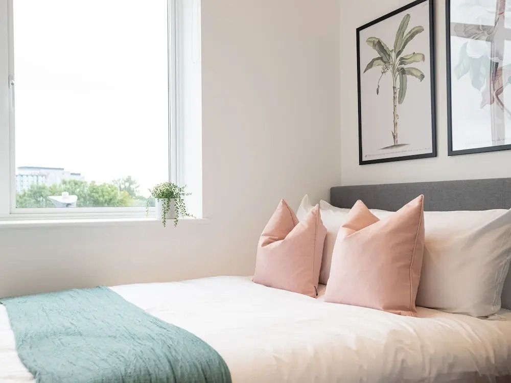 Gemütliches Schlafzimmer mit Palmenbild und großen Fenstern.