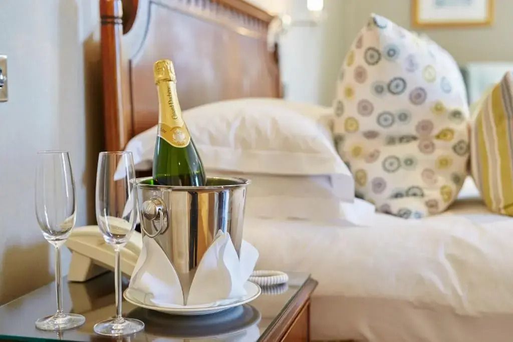 Champagnerflasche in einem Eiskübel mit Gläsern neben einem luxuriösen Bett