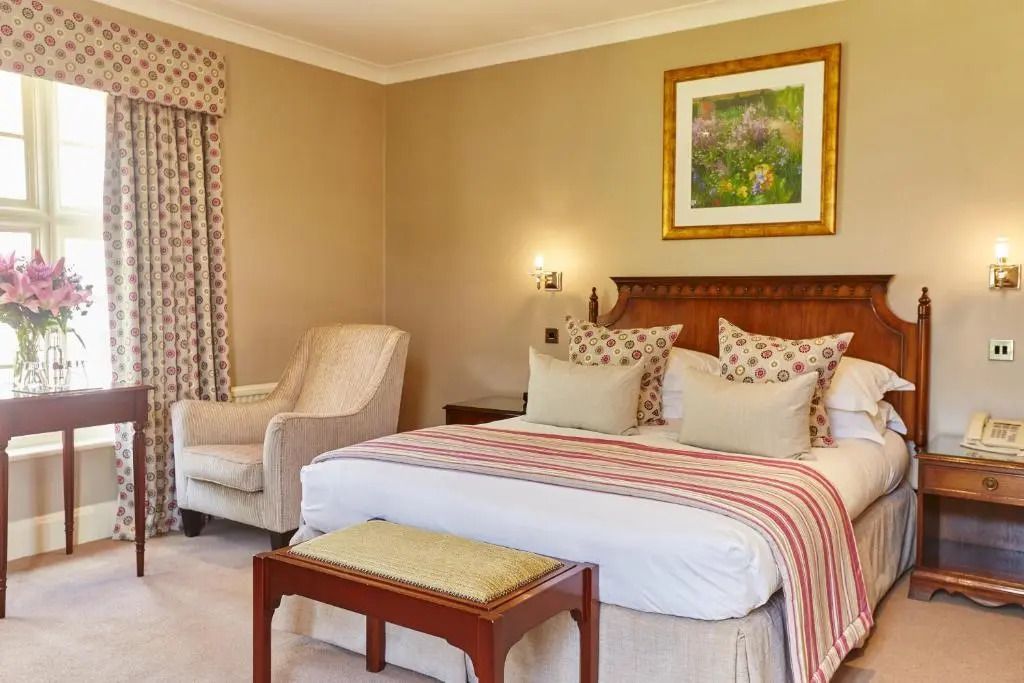 Elegantes Hotelzimmer mit Doppelbett und Sitzbereich in warmen Erdtönen.