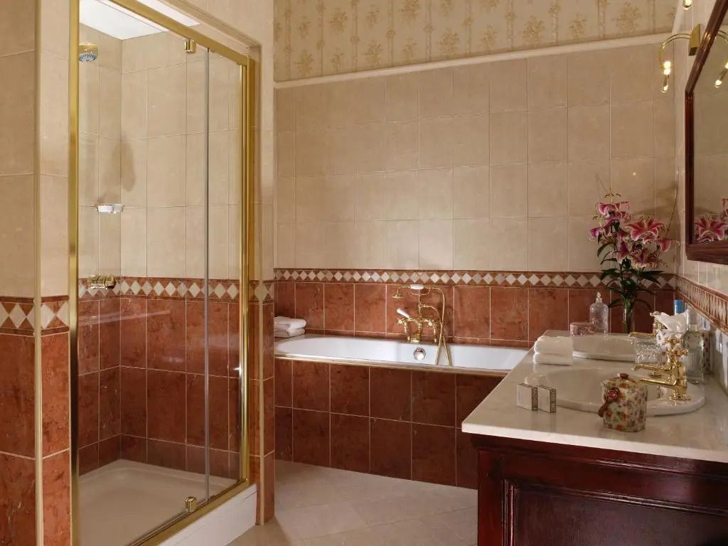 Elegantes Badezimmer mit Badewanne und vergoldeten Armaturen im Tylney Hall Hotel.