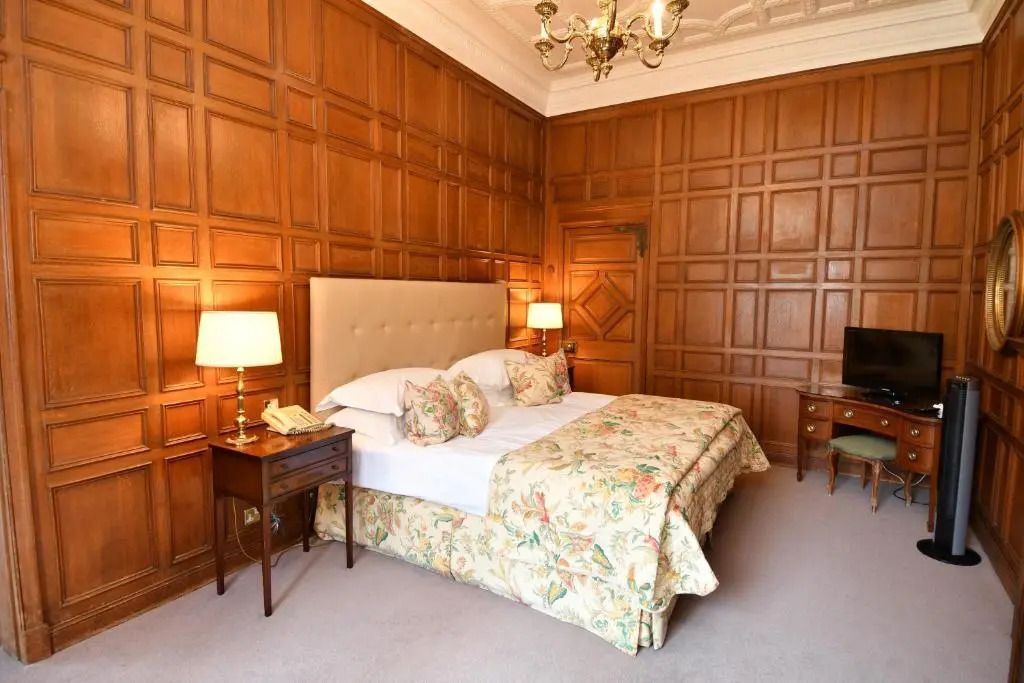 Gemütliches Schlafzimmer in einer Suite des Tylney Hall Hotels mit Holzwänden.