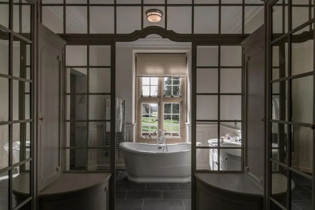 Exquisites Badezimmer mit freistehender Badewanne und großem Fenster im Tylney Hall Hotel.