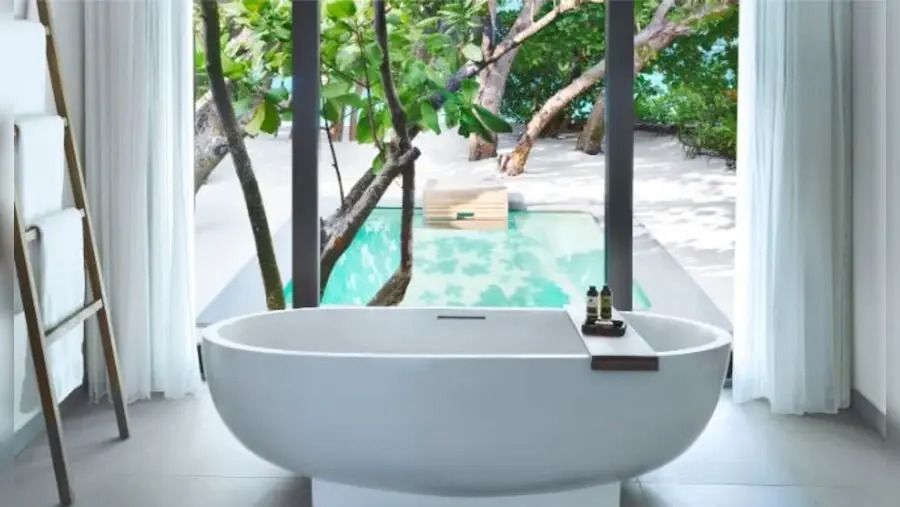 Freistehende Badewanne mit Blick auf den privaten Pool und Garten