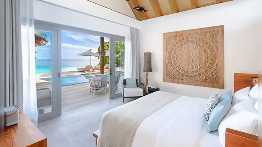 Luxuriöse Suite mit Blick auf Pool und Meer. Helle Einrichtung und großes Bett.