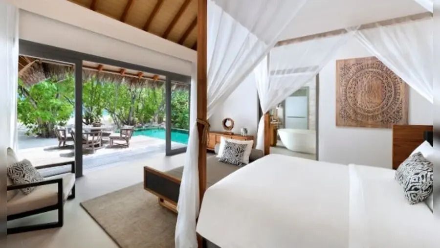 Schlafzimmer mit offenem Zugang zur Terrasse und Sitzbereich im Vakkaru Maldives.