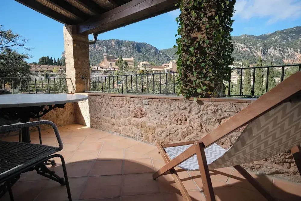 Terrasse mit Bergblick, Liegestuhl und Tisch im Deluxe Zimmer des Hotels.