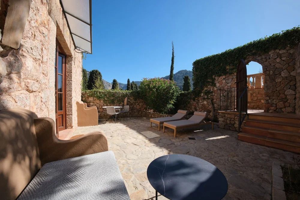 Sonnige Terrasse mit Liegestühlen, umgeben von grünen Pflanzen und Bergen