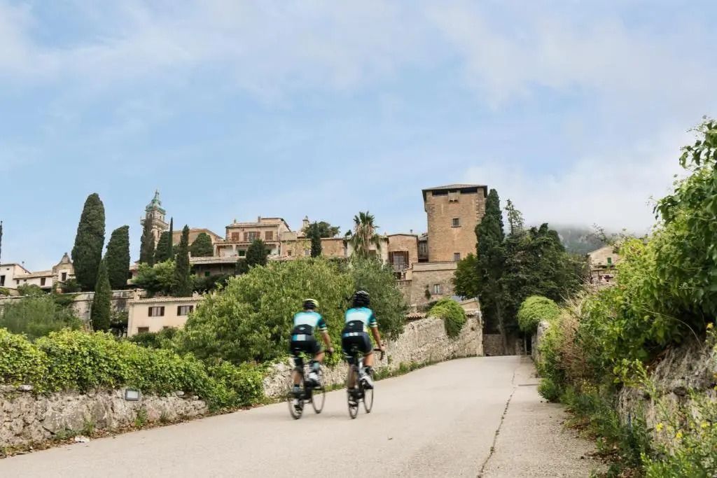 Zwei Radfahrer auf einer Straße mit Blick auf das Hotel Valldemossa.