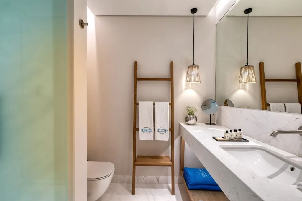Modernes Badezimmer mit Handtuchleiter, großer Spiegel und eleganter Beleuchtung.