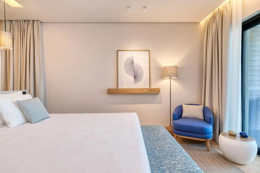 Modern eingerichtetes Doppelzimmer mit Kunstwerk und gemütlichem Sessel.
