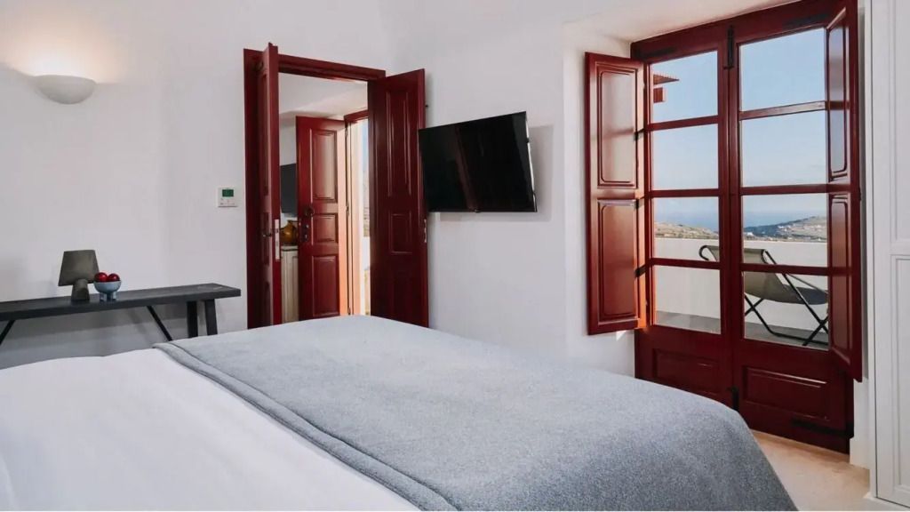 Zimmer mit Balkonzugang und Meerblick durch offene Fensterläden.