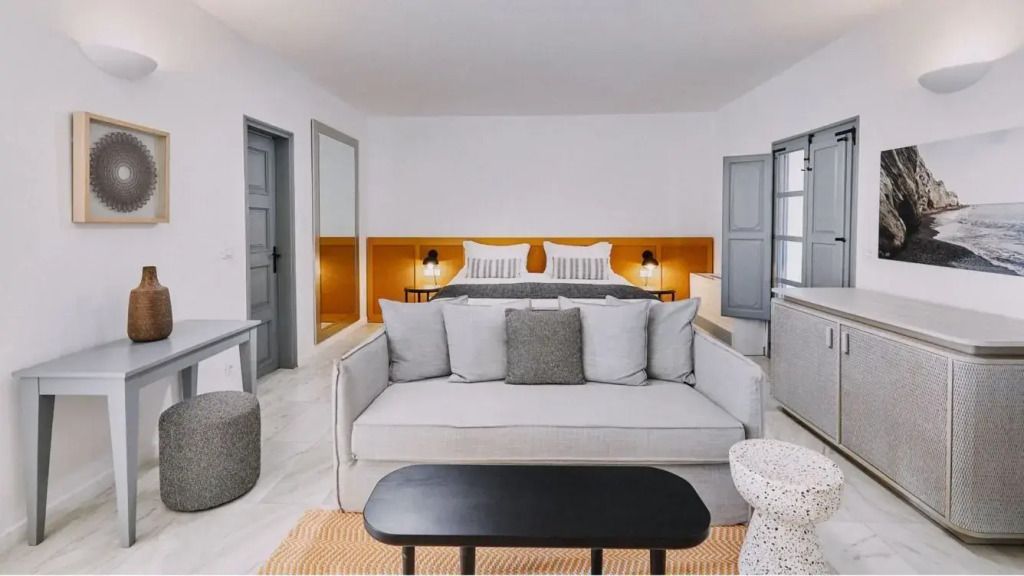 Elegantes Schlafzimmer mit Doppelbett und gemütlichem Sofa in neutralen Farbtönen